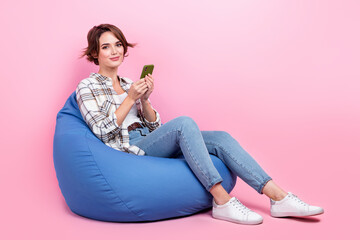 Obraz na płótnie Canvas Full size portrait of nice positive girl sit comfy bag use smart phone chatting isolated on pink color background