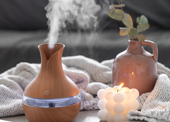 Spa composition with aroma oil diffuser lamp and candle on a blurred background.