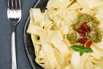 Pasta. Fettuccine with pesto sauce, ketchup and basil leaf
