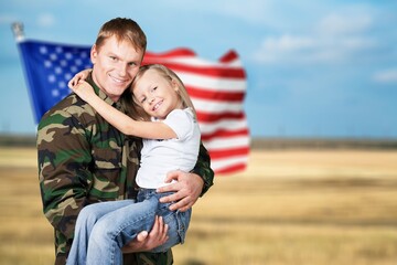 Military man carrying little child, american flag