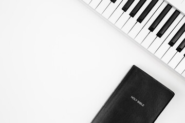 Fototapeta na wymiar Keyboard of a musical synthesizer and the holy Bible on a white background, top view, copy space.