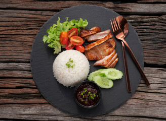 Grilled pork with fresh vegetable salad on a black plate over dark slate, stone or concrete background. Top view with copy space.