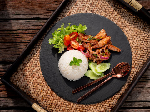 Rice with grilled pork neck salad thai food with herbs and spices ingredients, tradition northeast food delicious with fresh vegetables, Hot and spicy menu asian food on stone plate.