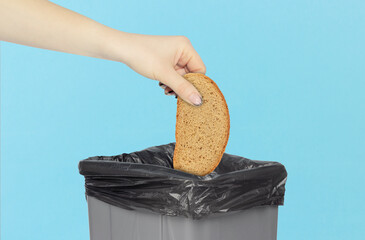 throwing a piece of bread into the trash can, bread in hand in front of the trash can, stale food...