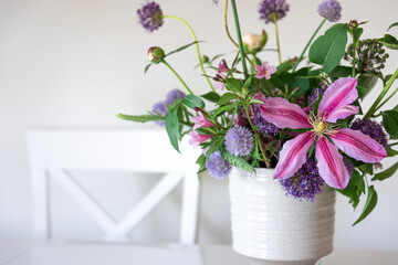 Vase with flowers from the garden in a white kitchen interior.