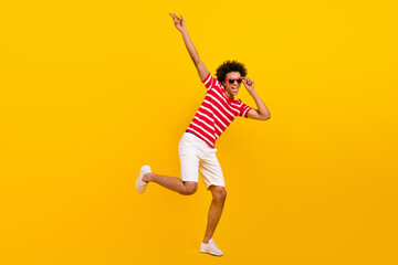 Fototapeta na wymiar Full length portrait funny guy excited dancer summer vacation wear shirt pants shoes sun specs isolated yellow color background