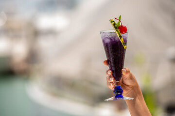 colorful gin tonic cocktails in glasses on on hand in yacht and sea background. hand cheers glass of cocktails cool drinks or Mocktail blended fruit margaritas, passionfruit drinks.