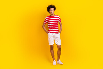 Fototapeta na wymiar Full length photo of cool cheerful man wear striped t-shirt smiling walking isolated yellow color background
