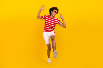Fototapeta na wymiar Full length photo of positive excited guy dressed red t-shirt dark glasses dancing having fun isolated yellow color background