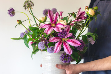 A man in an apron holds a vase of flowers, close-up.