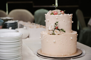 wedding white cake with tiers decorated with rose flowers on the table