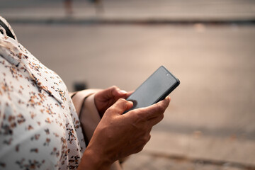 Close-up of a black female, holding a mobile phone, sending some messages.