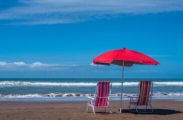 Beach chairs with a sun umbrella at the beach.