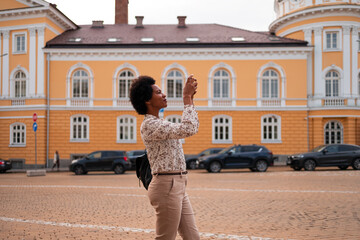 Photo of a black woman taking photos of a beautiful architecture with her phone.