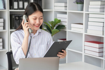 Asian businesswoman talking on the phone working in modern office Chat with clients for a new way of doing business in the office.