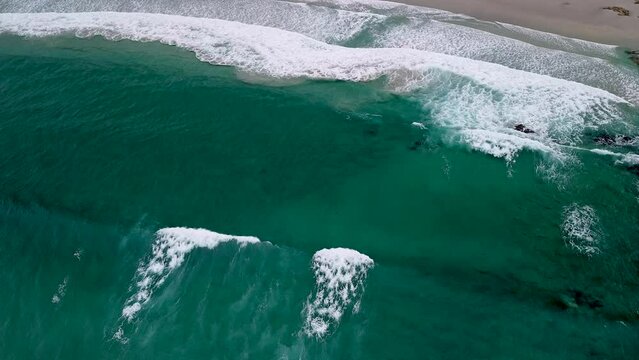 Aerial Shot Of Caion Beach Large Waves Crawling Gently To The Shore During Daytime In Coru&ntilde;a, Spain. top-down