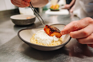 chef hand cooking grilled salmon fish fillet with creamy couscous