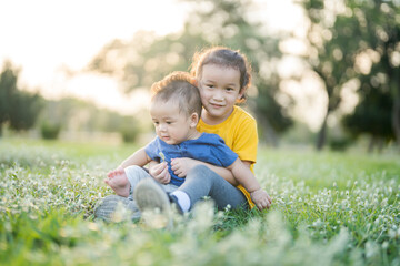 Naklejka na ściany i meble Little boy and girl sitting on the grass
