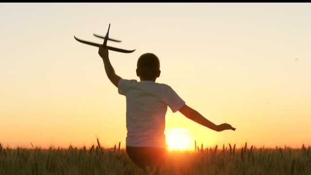 boy teenager child kid runs through field with wheat with toy plane his hands sunset, happy dream family, airplane toy, childhood dream becoming pilot astronaut playing park, airplane flight, kid