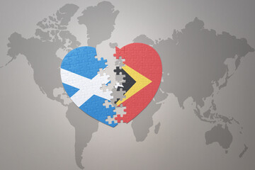 puzzle heart with the national flag of east timor and scotland on a world map background.Concept.