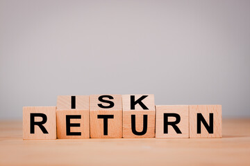 Obraz premium Investment concept about balance between risk and return with Flipping of wooden cubes block which print screen risk and return wording.