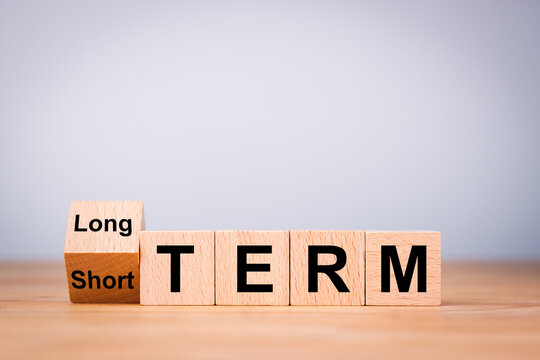 Business investment concept for Flipping od wooden cube block for change short term to long term.