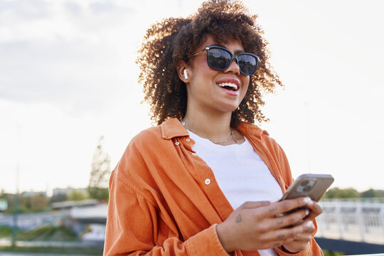 Black woman wearing sunglasses and looking at her mobile phone