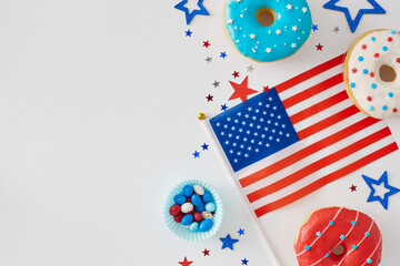 Obraz premium The idea of sweet celebration American Independence Day. Top view flat lay of national flag, red, blue, white donuts, delicious candies, confetti on white background with space for ad or text