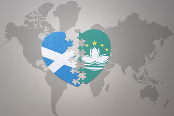 puzzle heart with the national flag of Macau and scotland on a world map background.Concept.