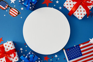 Obraz premium Idea for a Fourth of July party. Top view flat lay of patriotic gift boxes, fourth of July accessories, event confetti on blue background with blank circle for text