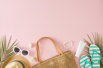 Trendy summer vacation concept. Top view flat lay of straw bag, hat, sunglasses, flip flops, shell bracelet, cream tube, tropical leaves, seashells on pastel pink background with empty space for ad