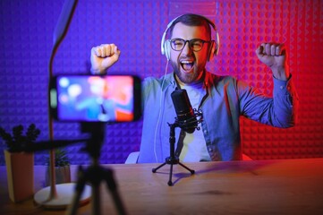 vlogger using smartphone to film podcast in studio. blogger with mobile phone, microphone and...