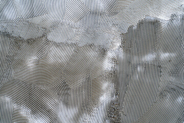 Surface of comb is made of gray adhesive plaster for walls, prepared for laying tiles. Patterns with a serrated spatula on tile glue - obrazy, fototapety, plakaty