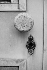 A worn vintage door handle in black and white.