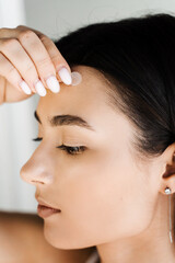Young woman using acne patches for treatment of pimple and rosacea close-up. Facial rejuvenation cleansing cosmetology. Girl with acne stick round acne patch on her cheek.