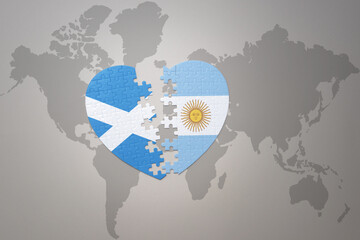 puzzle heart with the national flag of argentina and scotland on a world map background.Concept.