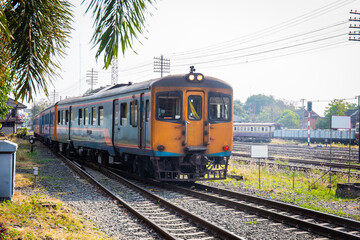 Old diesel train is stopping at a station in rural Thailand.
