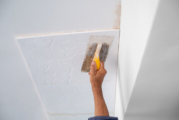 adhesive plaster application of styrofoam ceiling tiles of a home kitchen