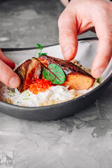 chef hand cooking grilled salmon fish fillet with creamy couscous
