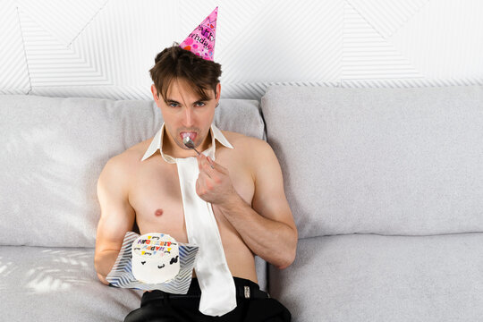 Shirtless man with a tie is celebrating his birthday, holds funny decorated cake