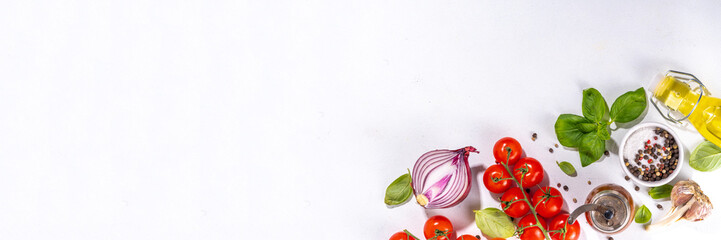 White cooking background with useful cooking italian Mediterranean ingredients - tomatoes, basil leaves, greens, olive oil, salt, pepper, garlic, flat lay white table top view copy space 