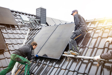 Tradesmen installing solar panels on the roof of a house