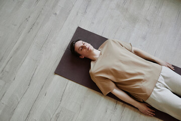 Minimal top view at young man lying down on floor in meditation with eyes closed, copy space