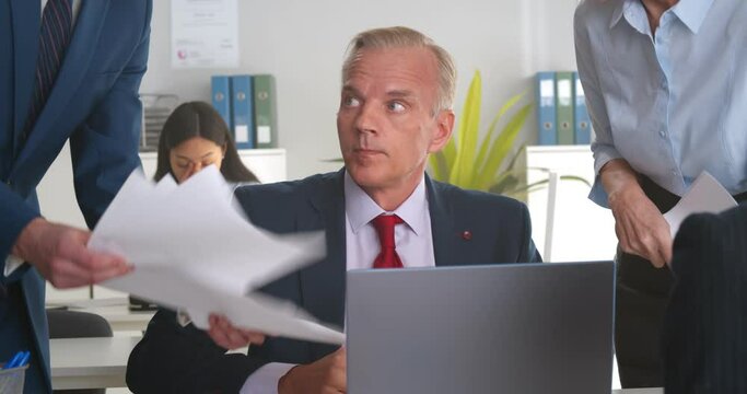 Mature businessman in office working under pressure from colleagues