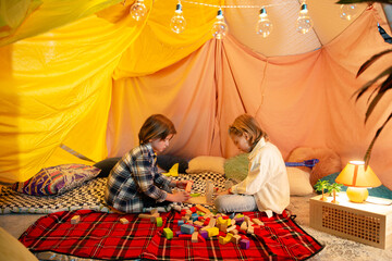 Obraz na płótnie Canvas Two boys one brunette and the other blond are playing with airplanes inside a big blanket fort