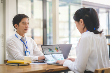 Obraz premium Image of corporate employees using laptop, working in co working space, sitting at shared desks.