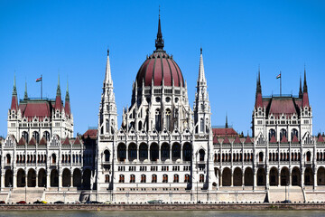 elevation detail of the neo gothic stone building along the Danube river. arched windows. tall tower with cupola. famous historic landmark building. popular tourist destination. blue sky. 