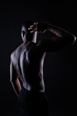 Athletic african american man topless, big muscles, dark background studio