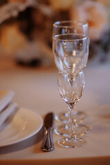 Three crystal or glass goblets on tables served with white ceramic plates and napkins for a banquet at a wedding or other festive event.