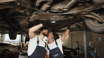 Two caucasian mechanics working about auto car engine service, technician having automotive job to maintenance or repair automobile in motor garage, business industrial auto car engin